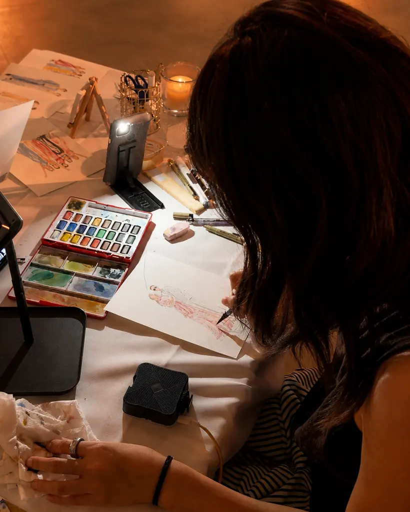 Charlotte GUO en train de dessiner un invité en direct, aquarelles et bougies sur la table
